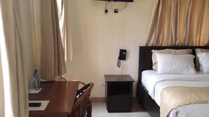 A hotel room with a bed, a desk, a chair, a TV mounted on the wall, and a telephone. - Bar BnB Spa and Barber (Nairobi)