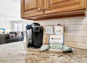 Eine Küche mit einer Keurig-Kaffeemaschine, einer Box mit dem Branding ScenicStays und einem Handtuch auf der Arbeitsplatte.