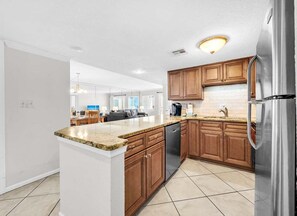 A modern kitchen with wooden cabinets, a stainless steel refrigerator, and a dishwasher. - (621) Gulf-Front Condo on 6th Floor, Sleeps 6, Kings, FREE Beach Service (Destin)