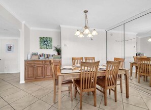 A dining area with a wooden table and chairs, a chandelier, and a kitchen area with cabinets and a countertop. - (621) Gulf-Front Condo on 6th Floor, Sleeps 6, Kings, FREE Beach Service (Destin)