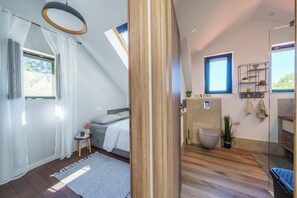 Une chambre à coucher avec un lit, une petite table et une fenêtre avec des rideaux.