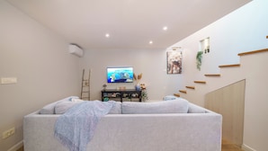 Sala de estar con sofá, televisor y escalera.