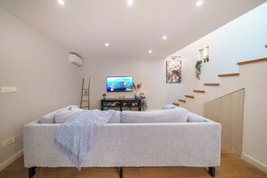 Ein Wohnzimmer mit Sofa, Fernseher und einer Treppe.