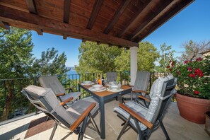 Une terrasse extérieure dotée d’une pergola en bois, d’une table dressée pour le repas et de chaises.