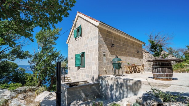 Un edificio de piedra con techo inclinado, un pequeño porche y vista al mar.