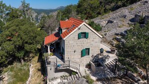 Un bâtiment en pierre avec un toit rouge, un balcon et une vue sur le paysage environnant.