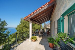 Un balcon avec vue sur la mer, des meubles d’extérieur et des plantes en pot.
