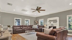 A spacious living room with a brown leather sofa, a white coffee table, and a ceiling fan. - Luxury and location in the Heartland (Wauchula)