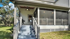 A house with a covered porch, a set of stairs leading to the entrance, and a screened area with a view of the outdoors. - Luxury and location in the Heartland (Wauchula)
