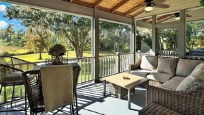 A covered outdoor patio with wicker furniture, ceiling fans, and a view of a golf course. - Luxury and location in the Heartland (Wauchula)