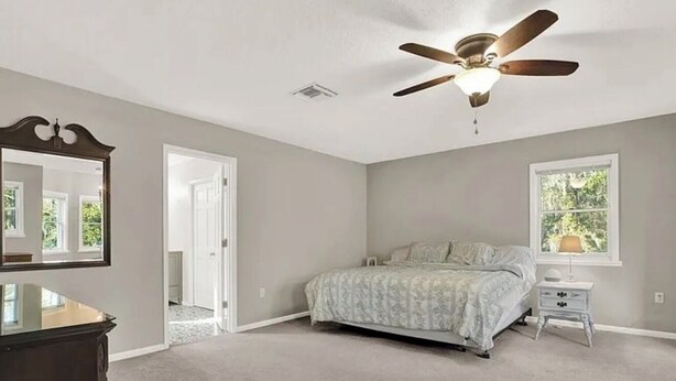 A bedroom with a bed, a ceiling fan, a dresser, a nightstand, and a window. - Luxury and location in the Heartland (Wauchula)