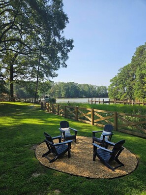 A lakeside deck with Adirondack chairs and a wooden fence. - Waterfront Retreat with Private Dock (Heathsville)