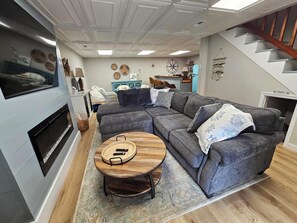 Un salon moderne avec un canapé d’angle, une table basse ronde en bois et une cheminée.