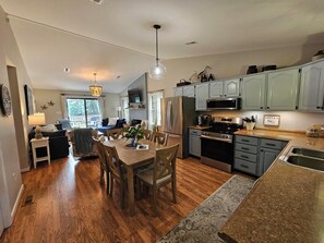 A spacious kitchen with modern appliances, a dining area with wooden furniture, and a view to the outside. - Waterfront Retreat with Private Dock (Heathsville)