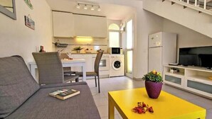 Un espacio habitable compacto con sofá, comedor, cocina y televisor.