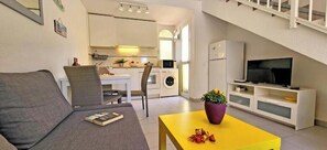 Ein gemütlicher Wohnbereich mit Sofa, Essplatz, Küchenzeile und Fernseher.
