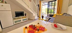 Ein Essbereich mit einem Tisch für zwei Personen, einem Fernseher und einer Treppe, die zu einer oberen Ebene führt.