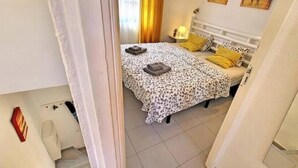 Un dormitorio con una cama, dos mesitas de noche y un tocador.