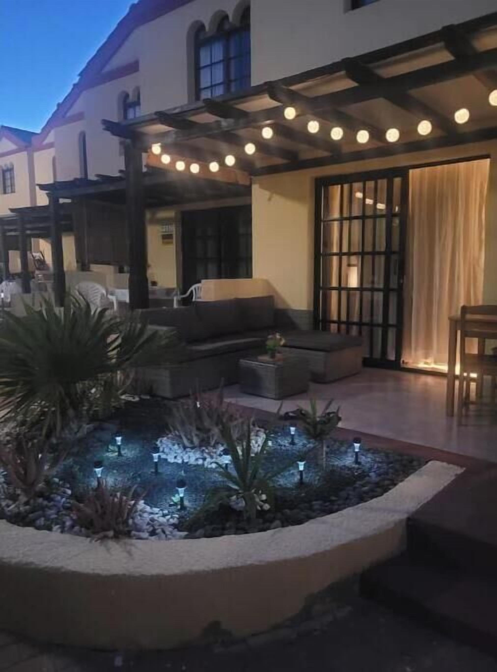 An outdoor patio area with a seating arrangement, a water feature, and string lights.