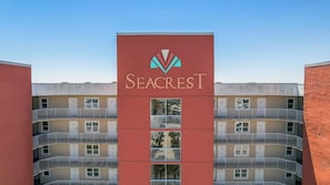 A multi-story building with balconies and a central sign for Seacrest. - 2BR Beachfront corner condo w private beach & hot tub ~ Sleeps 8 (Gulf Shores)