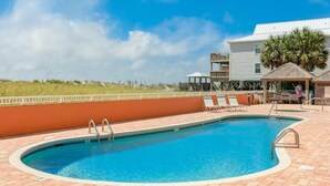 A swimming pool with a clear blue water, surrounded by a brick deck and a low wall. - 2BR Beachfront corner condo w private beach & hot tub ~ Sleeps 8 (Gulf Shores)