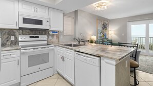 A modern kitchen with white cabinetry, a built-in oven, a microwave, and a dishwasher. - 2BR Beachfront corner condo w private beach & hot tub ~ Sleeps 8 (Gulf Shores)