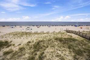 A beach with a wooden boardwalk leading to the water, sandy dunes, and beach umbrellas.