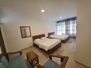 A hotel room with two beds, a small table, a chair, a mirror, and a window with curtains. - HILL SIDE RESORT - Ella (Ella)