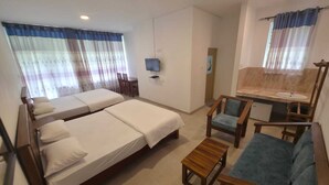 Una camera d'albergo con due letti, una televisione, una scrivania con una sedia e un divano.