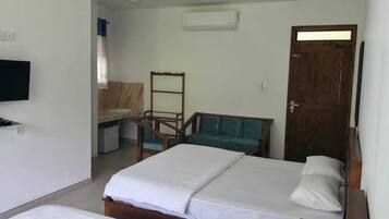 A hotel room with two beds, a desk, a chair, a television, and an air conditioning unit.