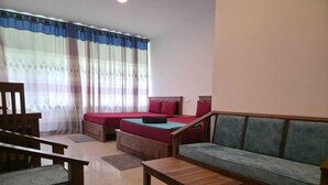 Um quarto com sofá, duas camas, uma mesa de madeira e uma cadeira.