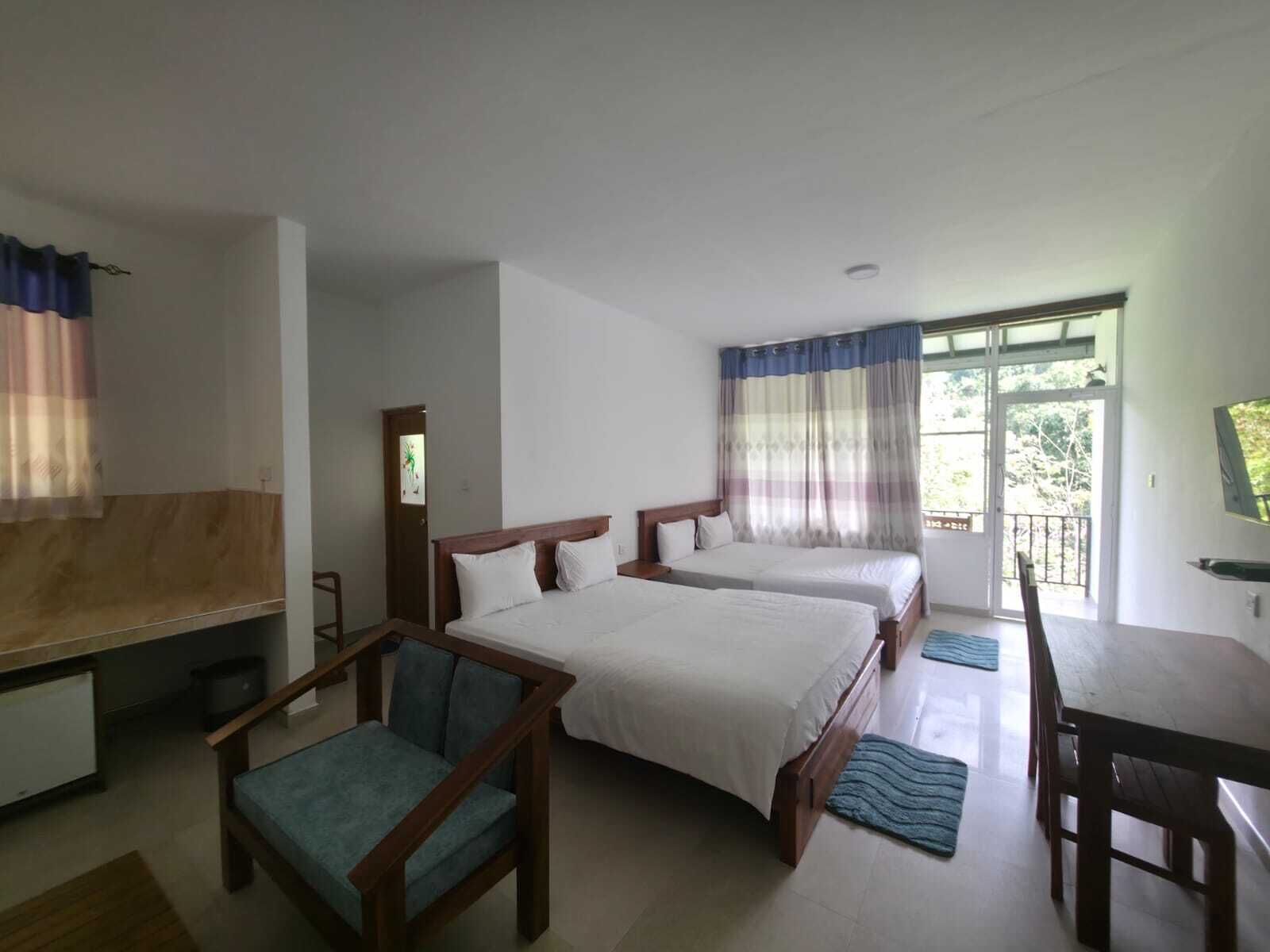 Habitación de hotel con dos camas, un escritorio, una silla y una ventana con cortinas.