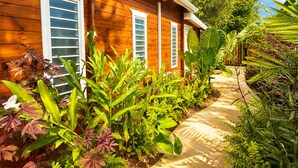 Uma casa de madeira com um caminho rodeado por vegetação exuberante.