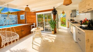 Cozinha moderna com área de refeições, uma cadeira suspensa e vista para o exterior.