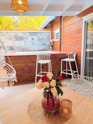 A wooden deck with a table and chairs, a wicker basket, and a vase with flowers. - Filao Cottage Bungalow with Private Pool Near the Beaches—Adults Only (Sainte-Rose)