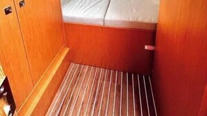 Uma cabana compacta com beliche, uma pequena janela e piso de madeira.