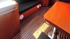 Um pequeno espaço com uma mesa de madeira, um banco acolchoado e um painel de controle.