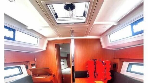 Um espaço interior acolhedor, com uma mesa central, assentos e um claraboia.