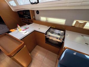 A compact kitchen with a countertop, oven, and a small sink. - Sun Odyssey 410 - POLARIS (Dalmacija Marina)