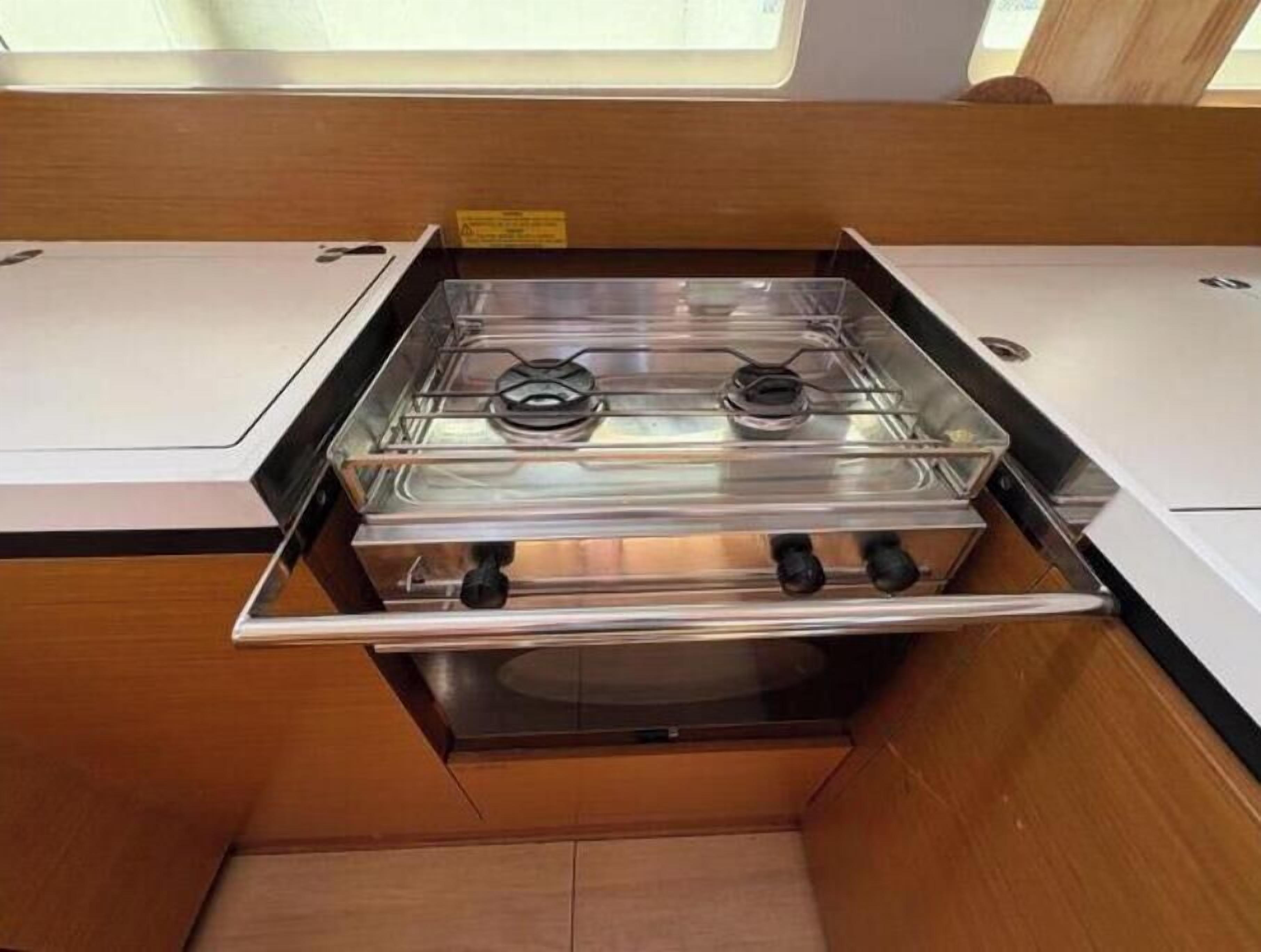 A compact kitchen with a gas stove, a sink, and a window above the countertop.