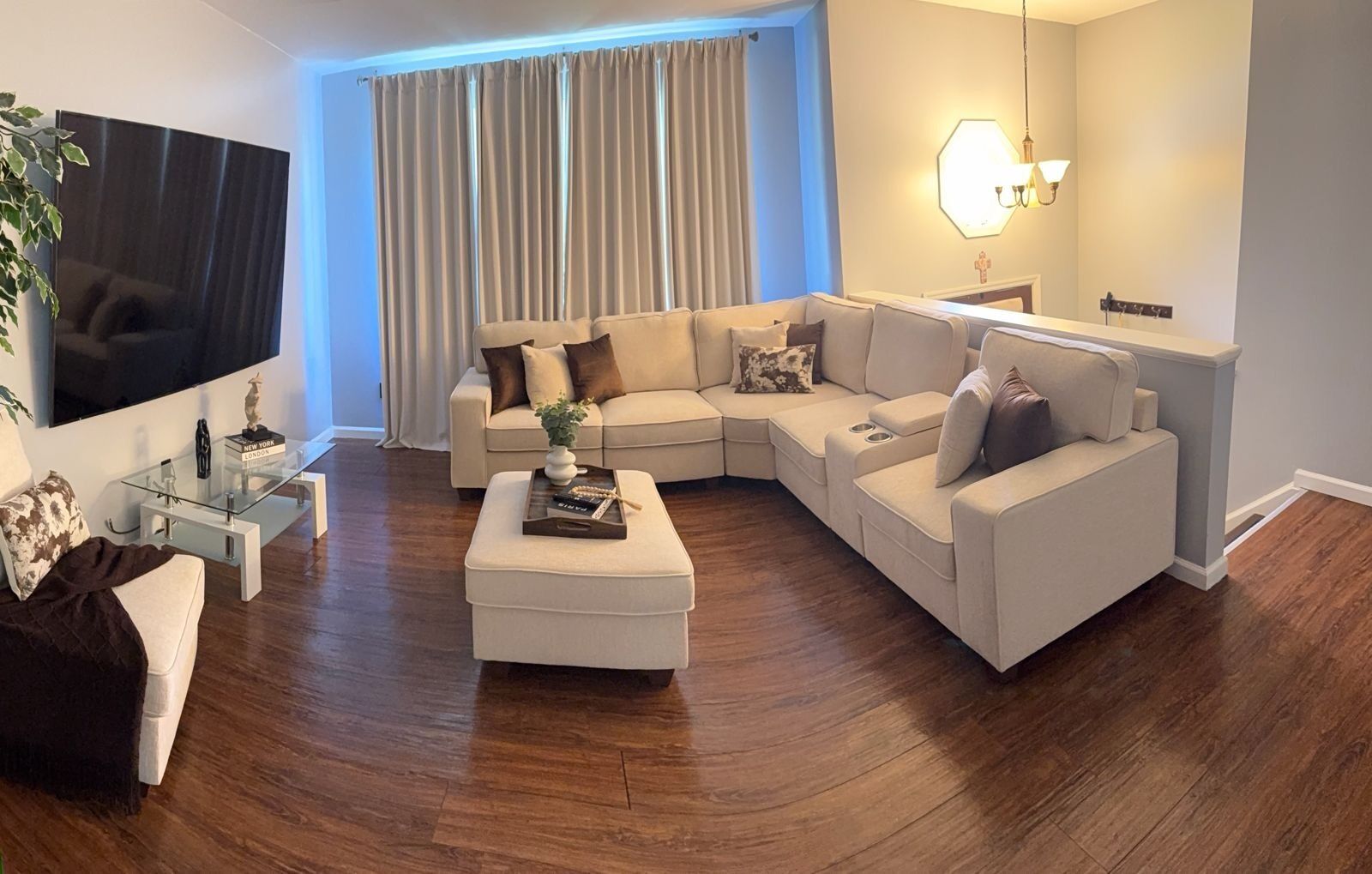 Ein modernes Wohnzimmer mit einem Ecksofa, einem Glastisch und einem Flachbildfernseher.