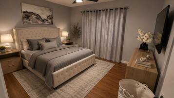 A bedroom with a bed, nightstands, a ceiling fan, a large window with curtains, a TV, and a small table with decorative items.