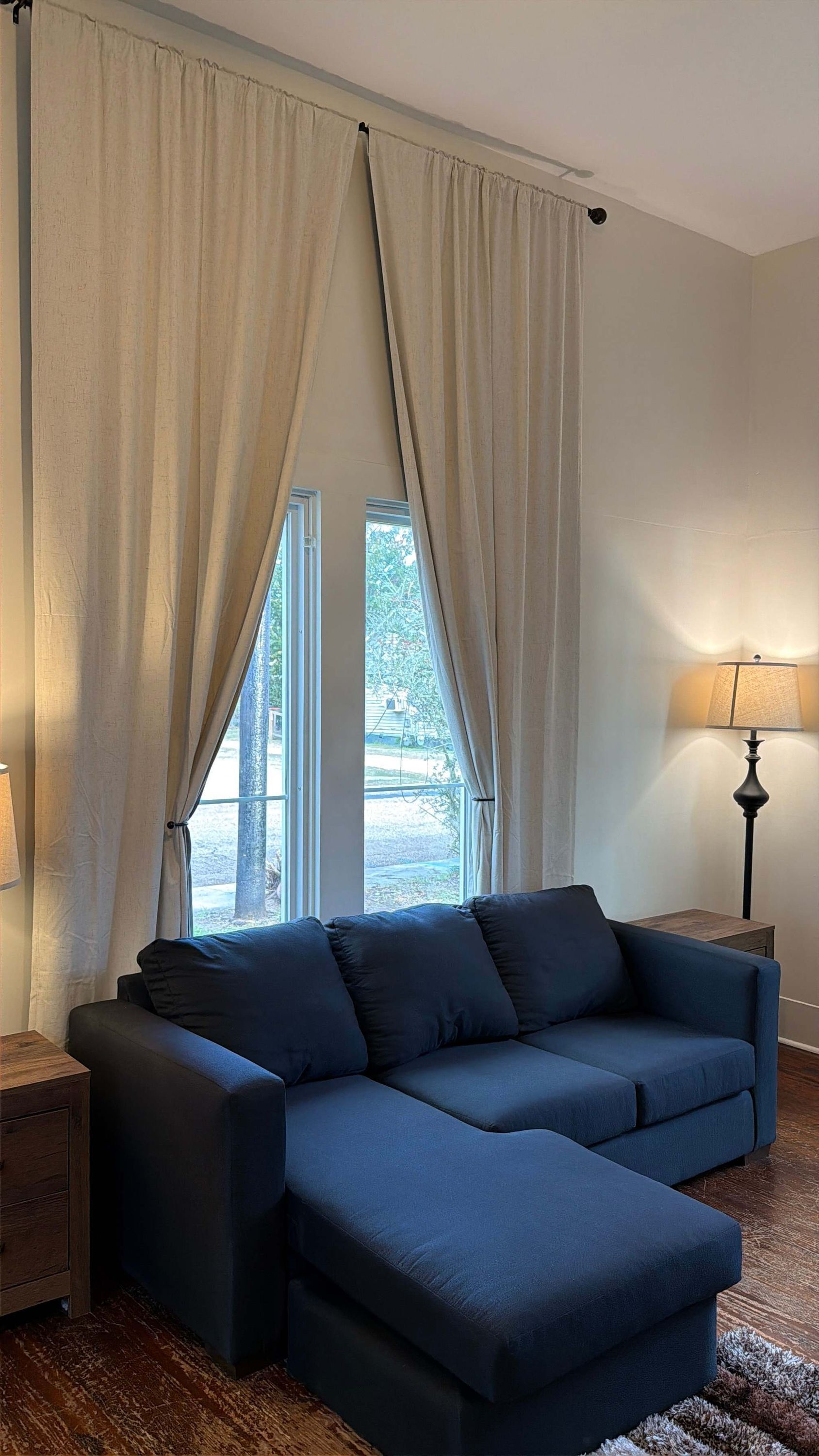 Quarto com sofá de canto, uma luminária e vista através de grandes janelas.