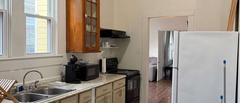 A kitchen with a double sink, wooden cabinets, a stove, and a refrigerator.