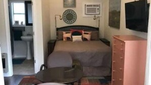 Ein Schlafzimmer mit einem Bett, einem Schminktisch, einem Fernseher, einer Wanduhr und einem Fenster.