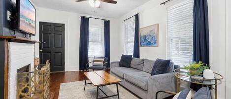 A living room with a sofa, armchair, coffee table, and a television.