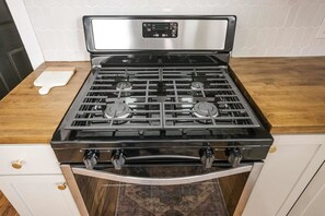 A kitchen with a black gas stove, stainless steel range hood, and a wooden countertop. - Group-friendly Lafayette Stay (Lafayette)