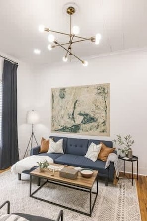 Uma sala de estar com um sofá azul, uma mesa de centro e um lustre moderno.