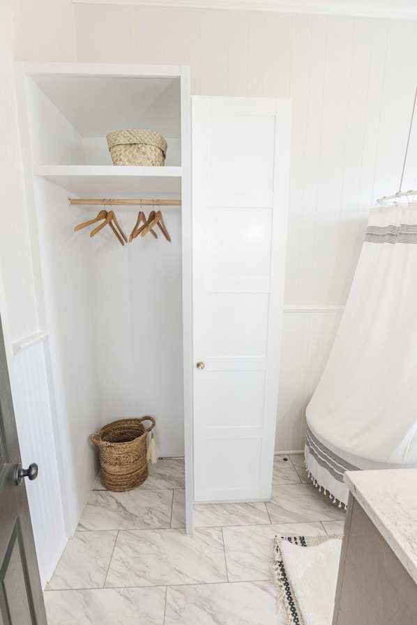 A bathroom with a white vanity, a shower curtain, and a tiled floor. - Group-friendly Lafayette Stay (Lafayette)