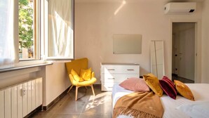 A bedroom with a bed, a chair, a dresser, a mirror, and a window with curtains. - Casa Bonvicino Citt Studi (Milan)